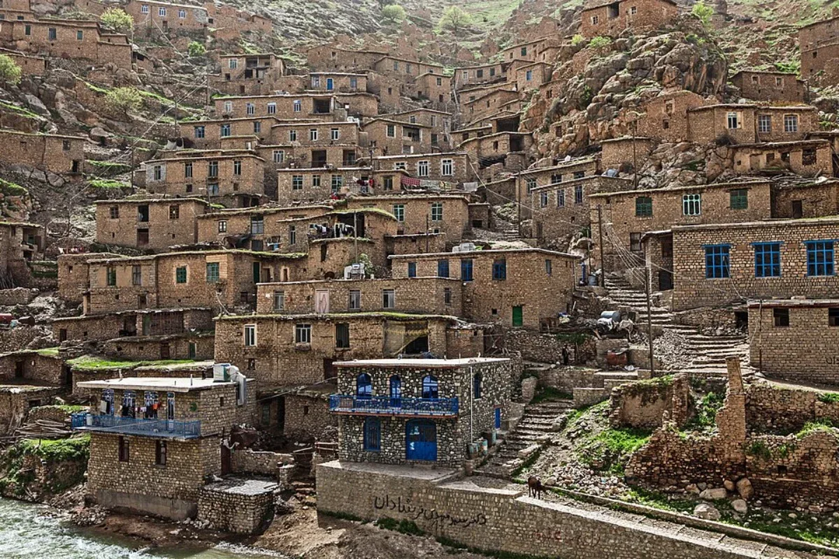 نمای روبه‌روی خانه‌های سنگی پلکانی پالنگان با پنجره‌ها و بالکن‌های آبی